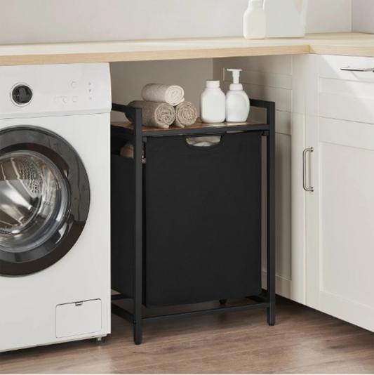 Panier à linge sale avec serviette sur son étagère à coter d'une machine à leaver