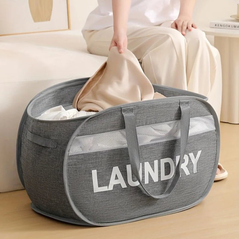 panier à linge pliable grande capacité gris avec du linge dedans dans une chambre